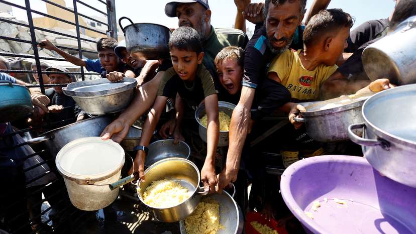 Palestinians wait to receive food from a charity kitchen, in Gaza City