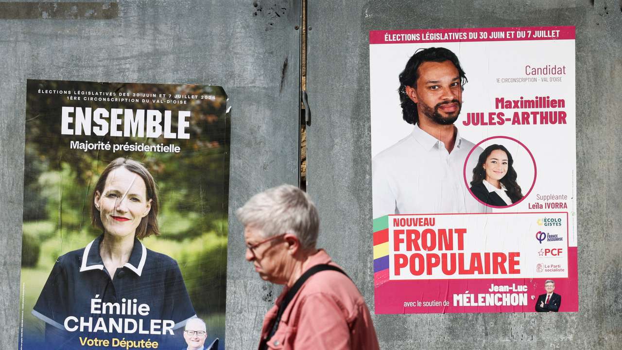 A person walks past election campaign posters prior to the second round of the early French parliamentary elections, in Magny-en-Vexin