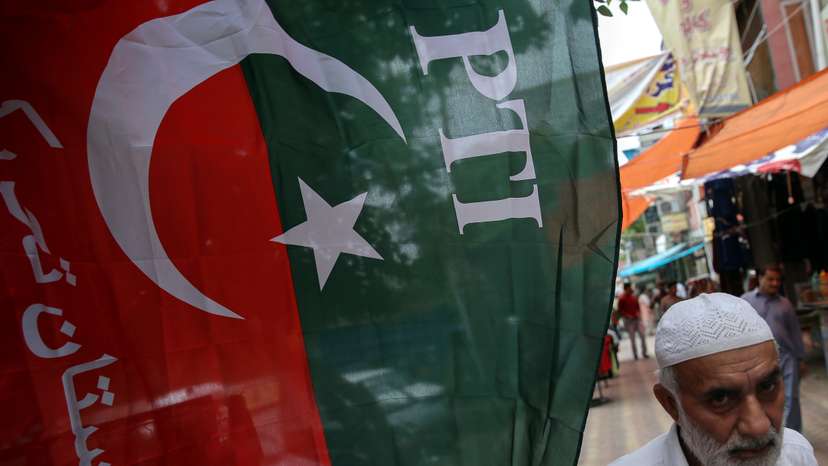 A man walks past a flag of the Pakistan Tehreek-e-Insaf (PTI) at a market, a day after general election in Islamabad