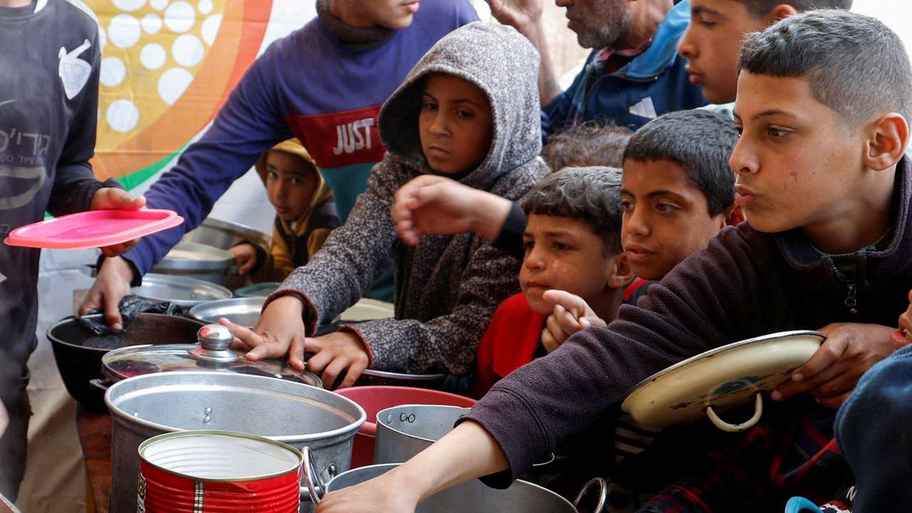 FILE PHOTO: FILE PHOTO: Palestinians gather to receive food cooked by a charity kitchen, in Khan Younis