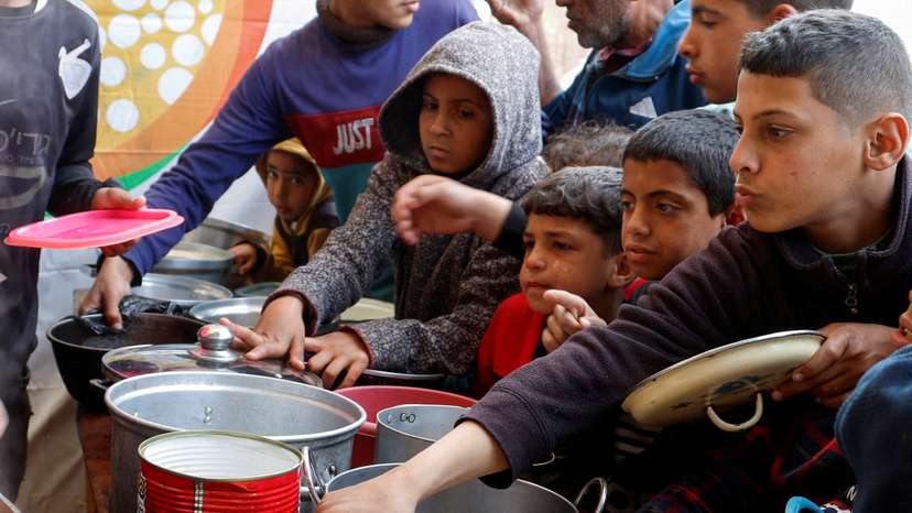 FILE PHOTO: FILE PHOTO: Palestinians gather to receive food cooked by a charity kitchen, in Khan Younis