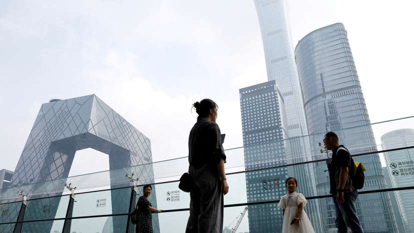FILE PHOTO: People stand at a shopping mall near the CCTV headquarters and China Zun skyscraper, in Beijing's central business district (CBD)