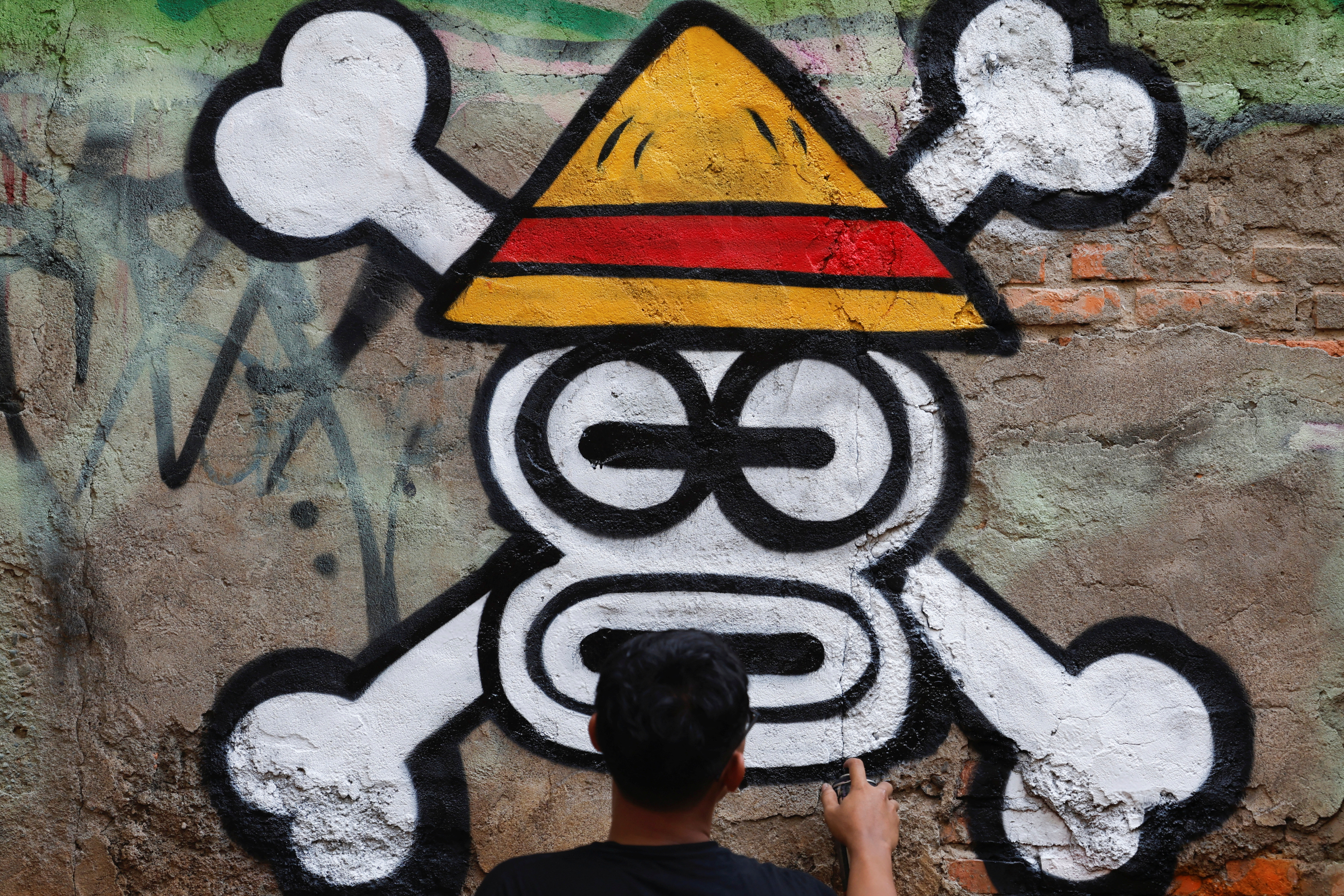 Kemas Muhammad Firdaus, 28, paints a mural depicting a Jolly Roger from the popular Japanese anime and manga series 'One Piece' in Bekasi