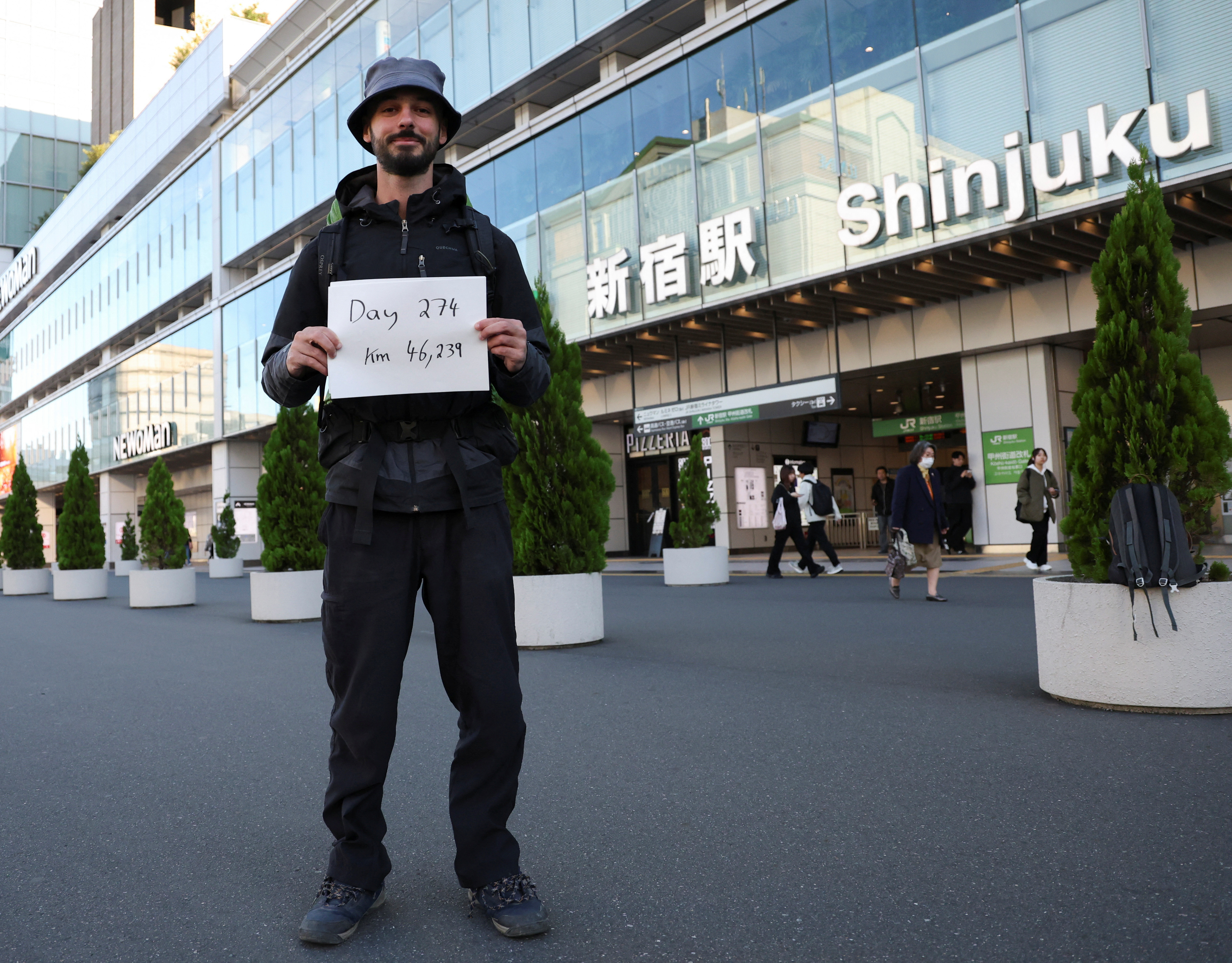 Omar Nok, 30-year-old Egyptian who travelled on road from Cairo to Tokyo, holds a sign written the days and distance he travelled on the road in front of Shinjuku station in Tokyo