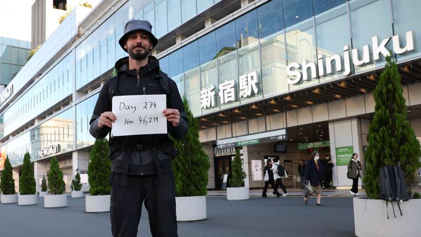 Omar Nok, 30-year-old Egyptian who travelled on road from Cairo to Tokyo, holds a sign written the days and distance he travelled on the road in front of Shinjuku station in Tokyo