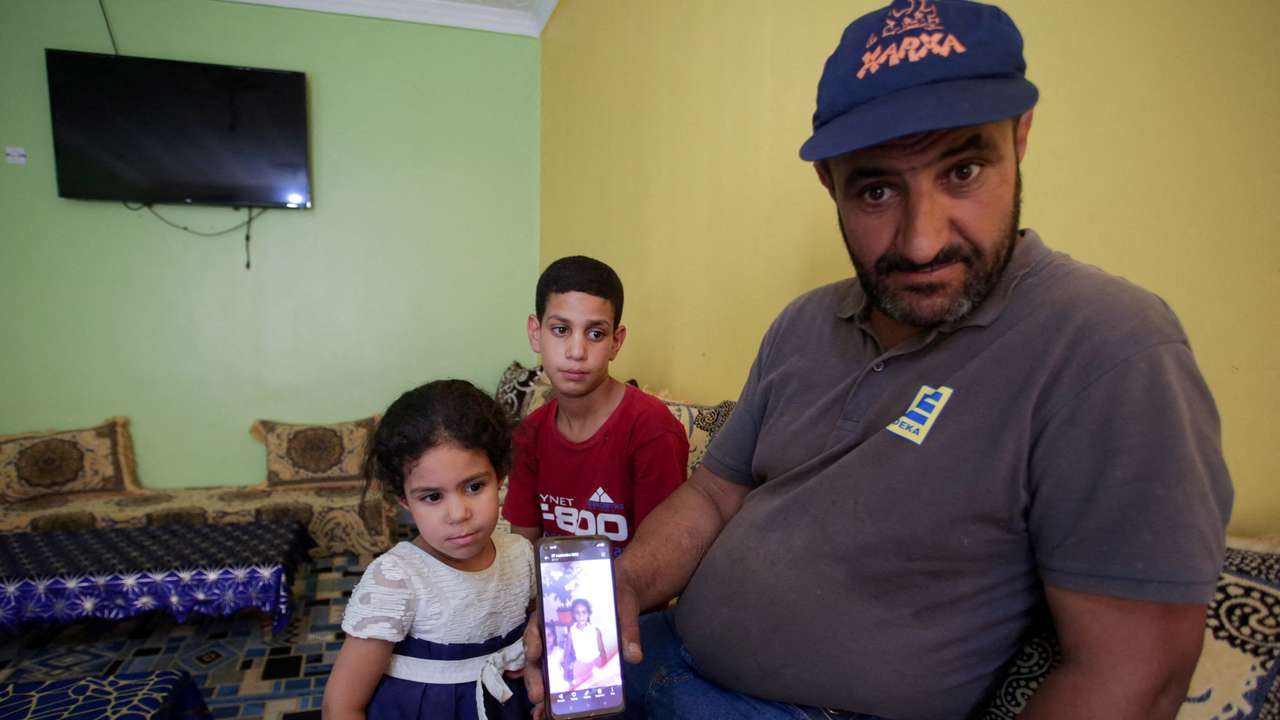 Amar, father of Algerian boxer Imane Khelif, sits with his children as he shows a picture of Imane when she was young, inside his house