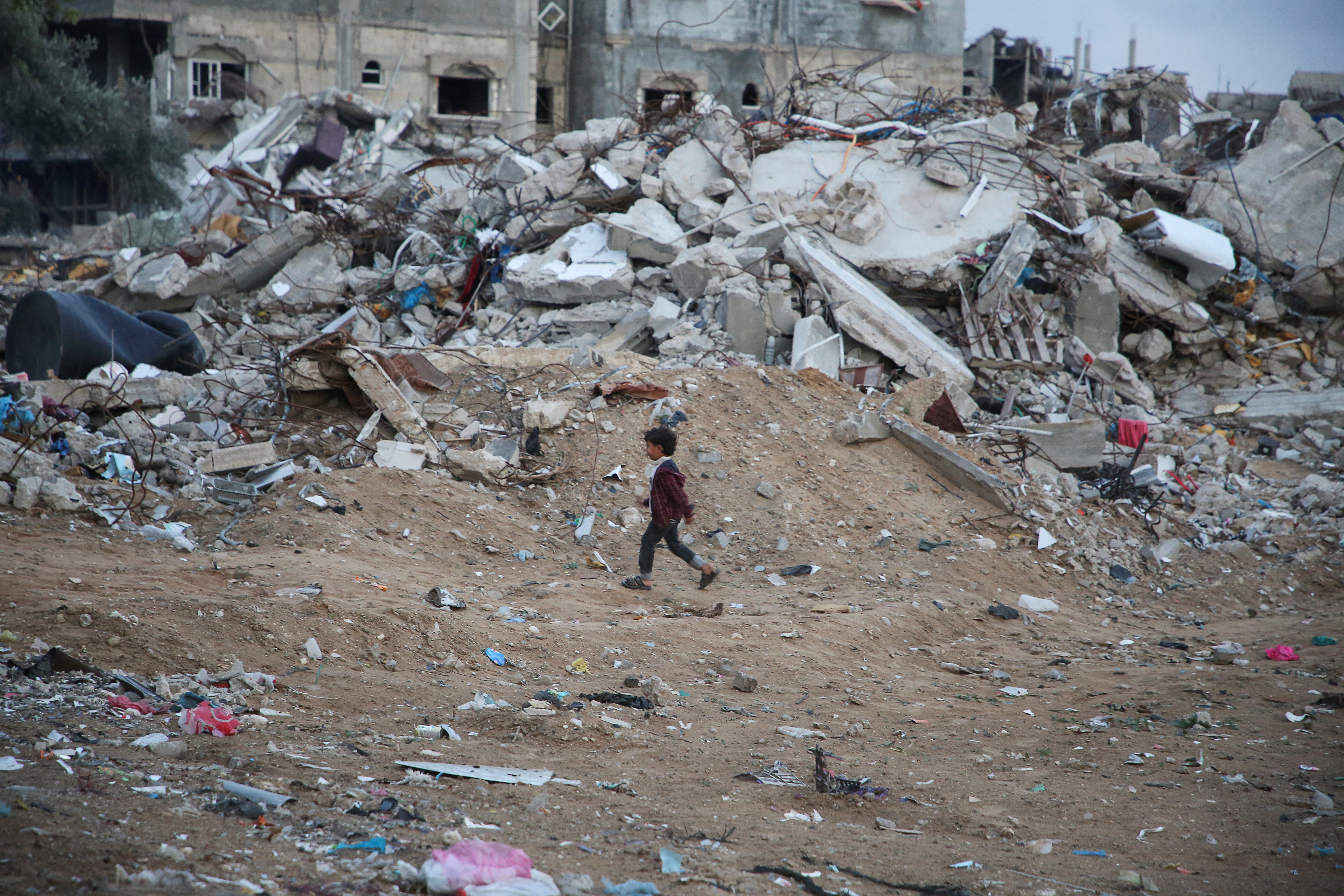 A Palestinian child walks past the rubble of a building destroyed during the Israeli offensive, amid a ceasefire between Israel and Hamas, in Rafah