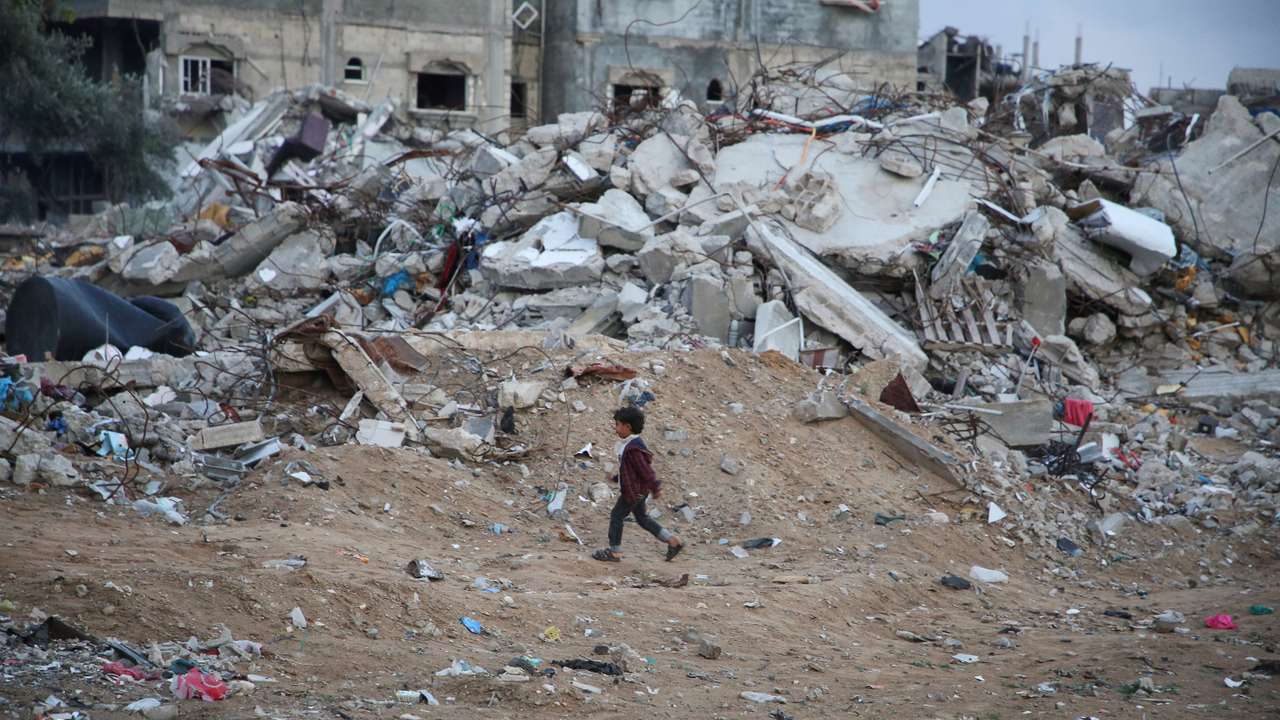 A Palestinian child walks past the rubble of a building destroyed during the Israeli offensive, amid a ceasefire between Israel and Hamas, in Rafah