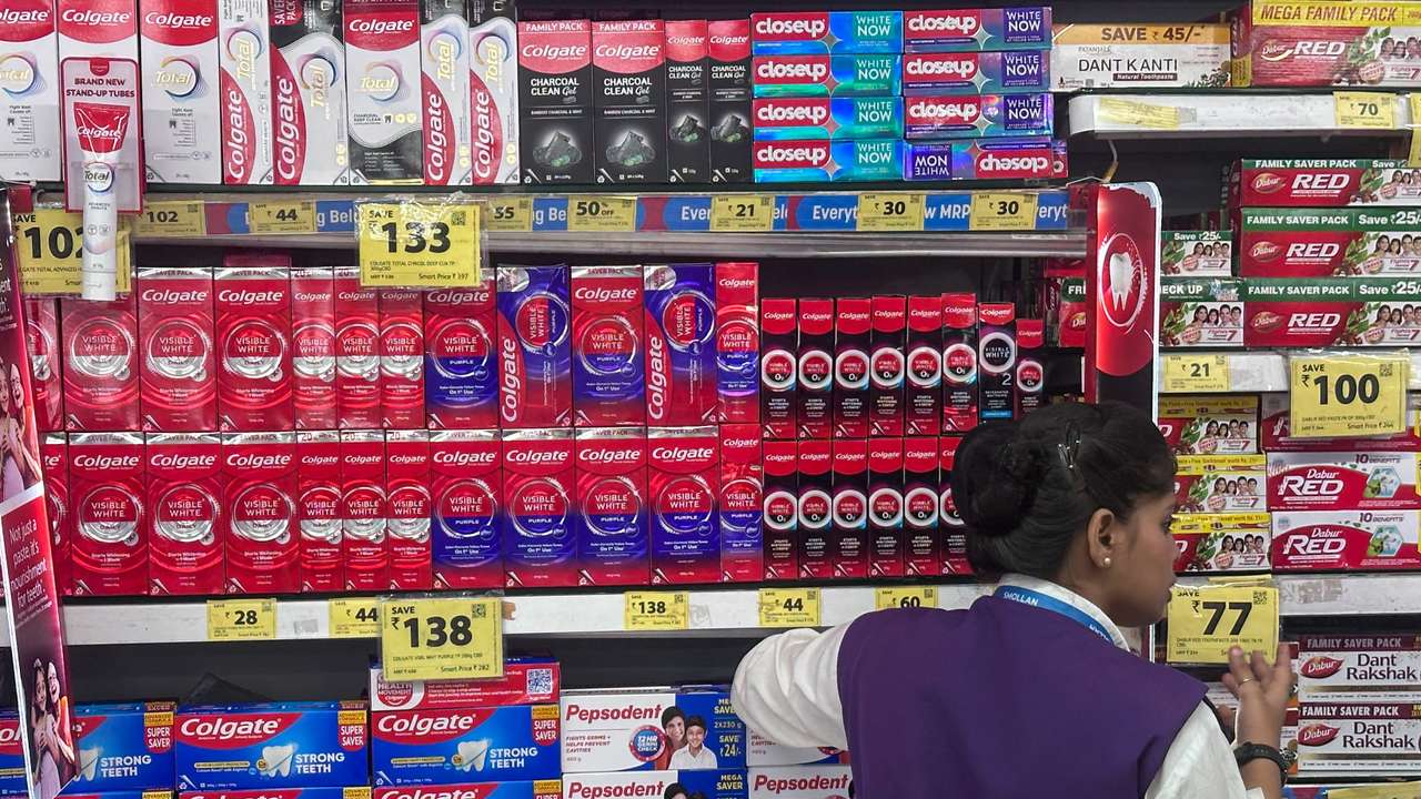 A woman stands next to toothpaste boxes at a supermarket in Mumbai