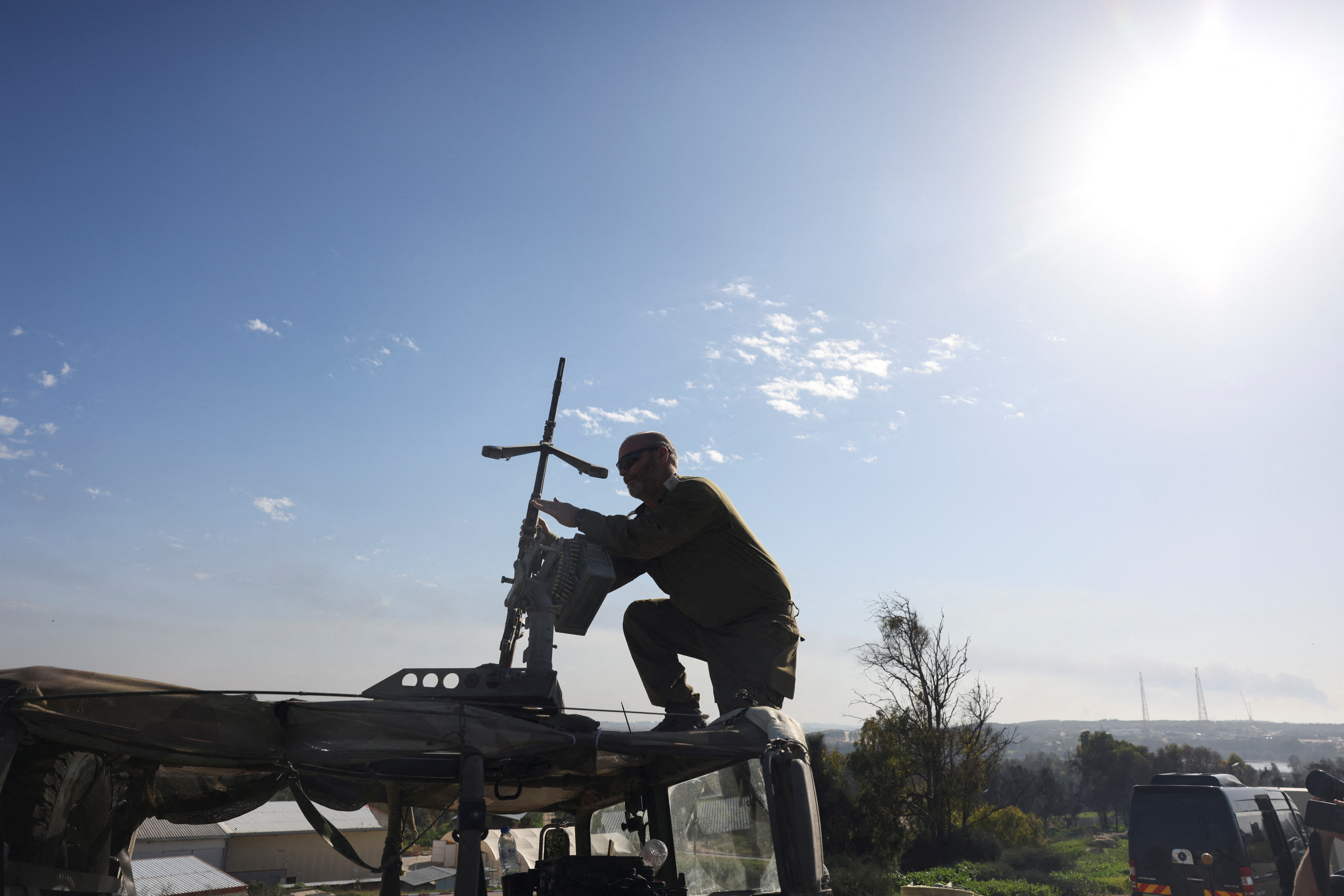 An Israeli soldier adjusts a weapon on top of a vehicle, amid the ongoing conflict between Israel and the Palestinian Islamist group Hamas, near Israel's border with Gaza