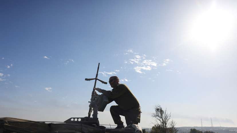 An Israeli soldier adjusts a weapon on top of a vehicle, amid the ongoing conflict between Israel and the Palestinian Islamist group Hamas, near Israel's border with Gaza