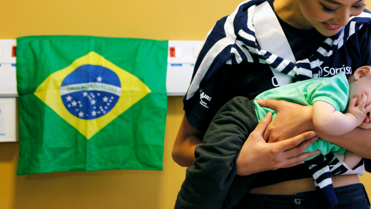 Luo Zilin carries a child with a cleft lip at a hospital during the "Operation Smile" event in Sao Paulo