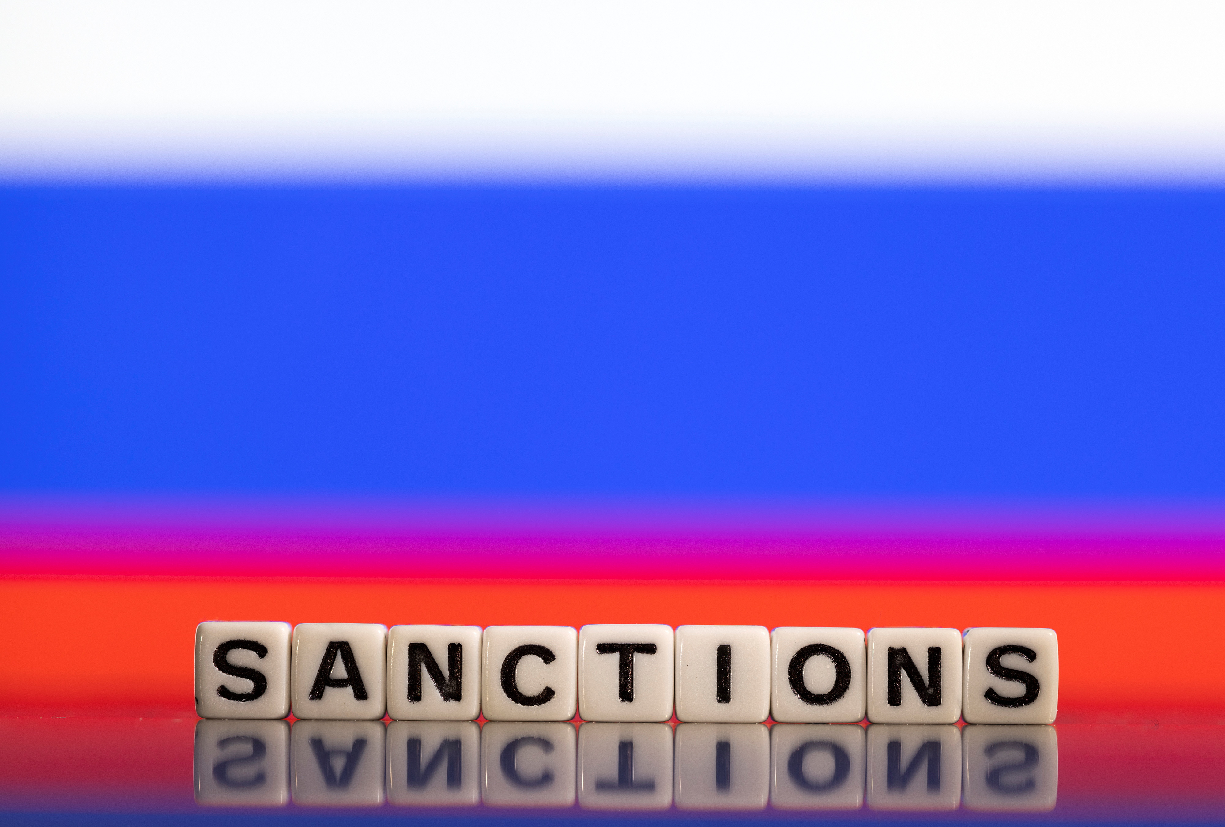 Illustration shows letters arranged to read "Sanctions" in front of Russian flag colors