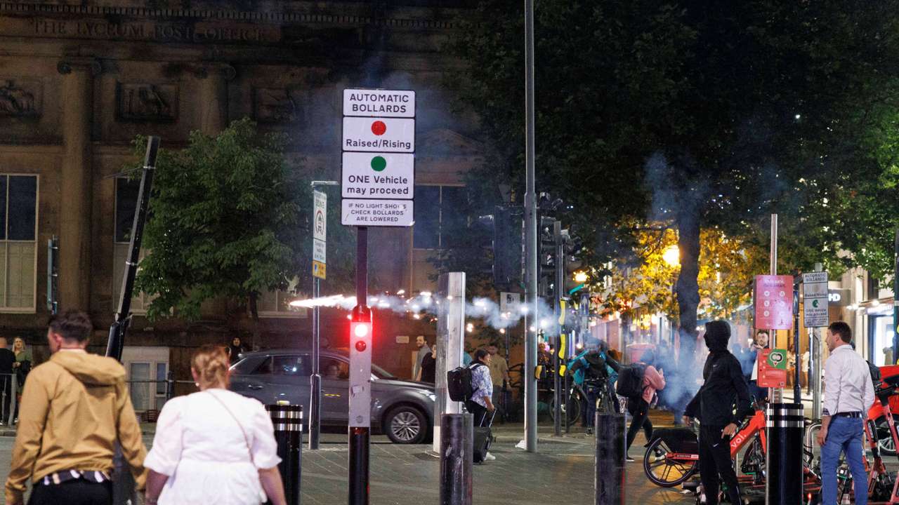 Protestors throw fireworks as the riots continue into the night in Liverpool