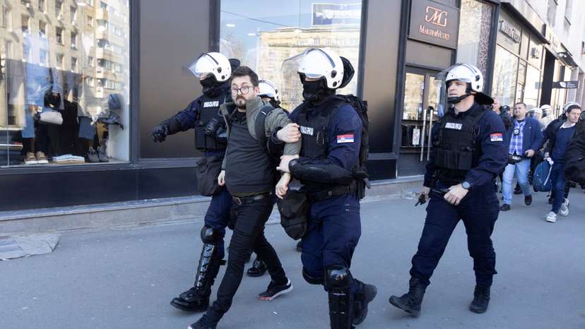 Police officers detain people during a protest in Belgrade