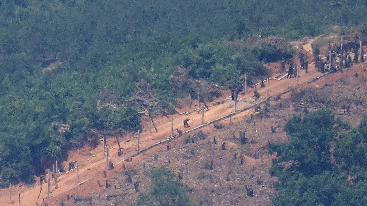 North Korean people work on a military fence near their guard post at the inter-Korean border