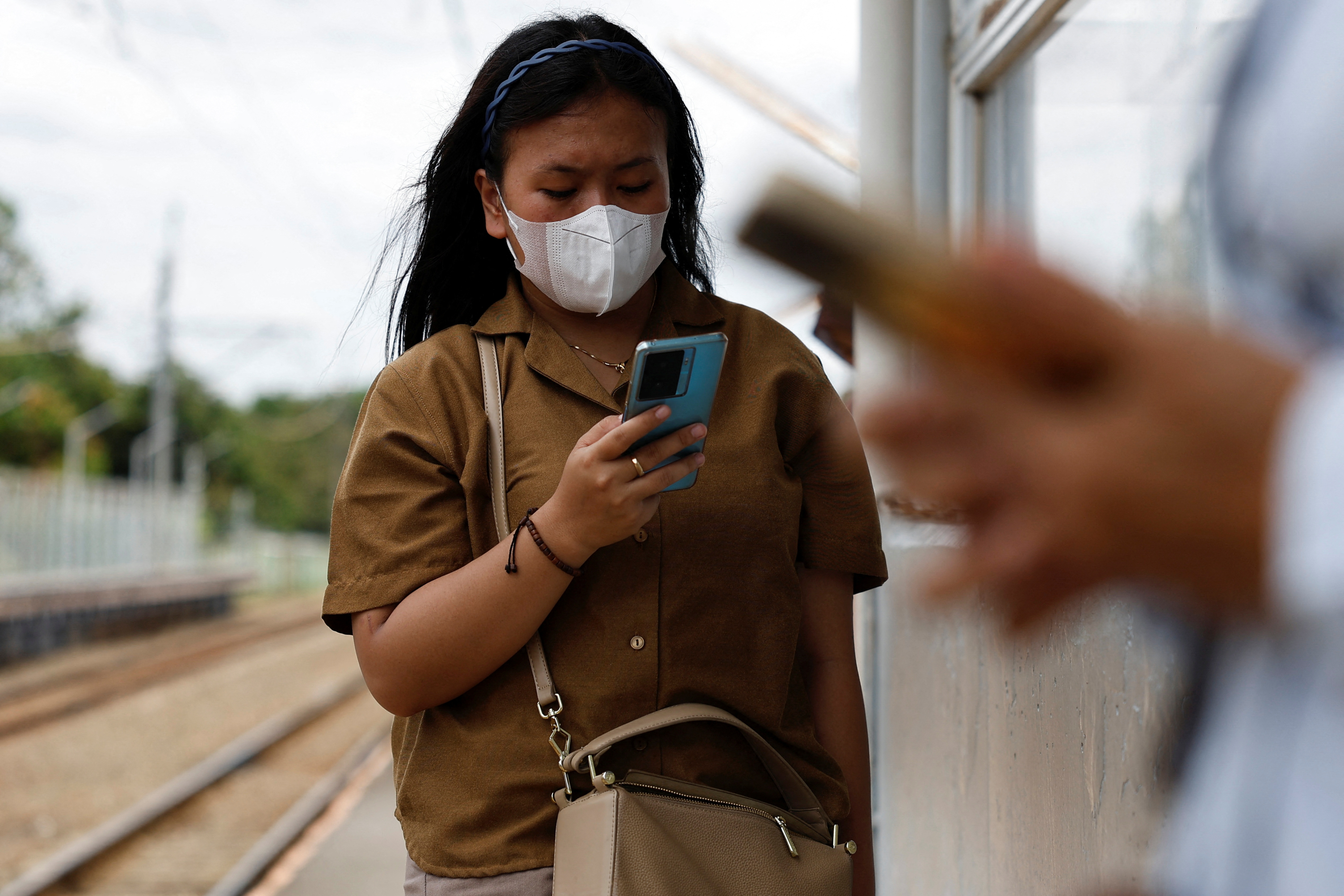 Woman uses smartphone while waiting for a train at a station in South Tangerang, on the outskirts of Jakarta