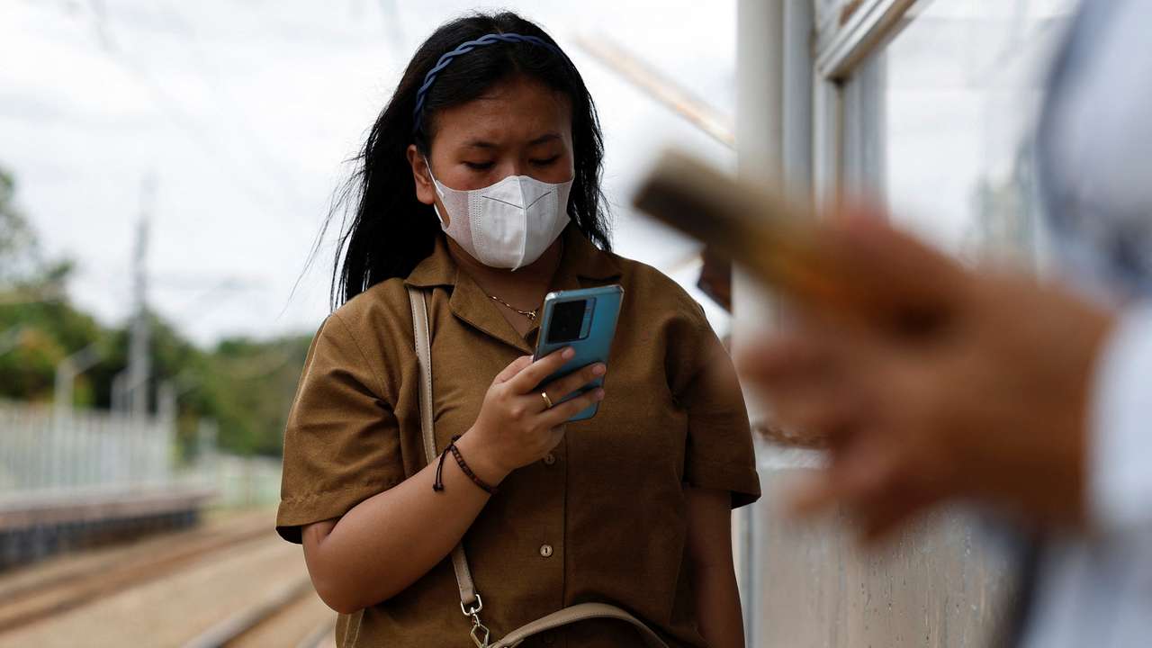 Woman uses smartphone while waiting for a train at a station in South Tangerang, on the outskirts of Jakarta