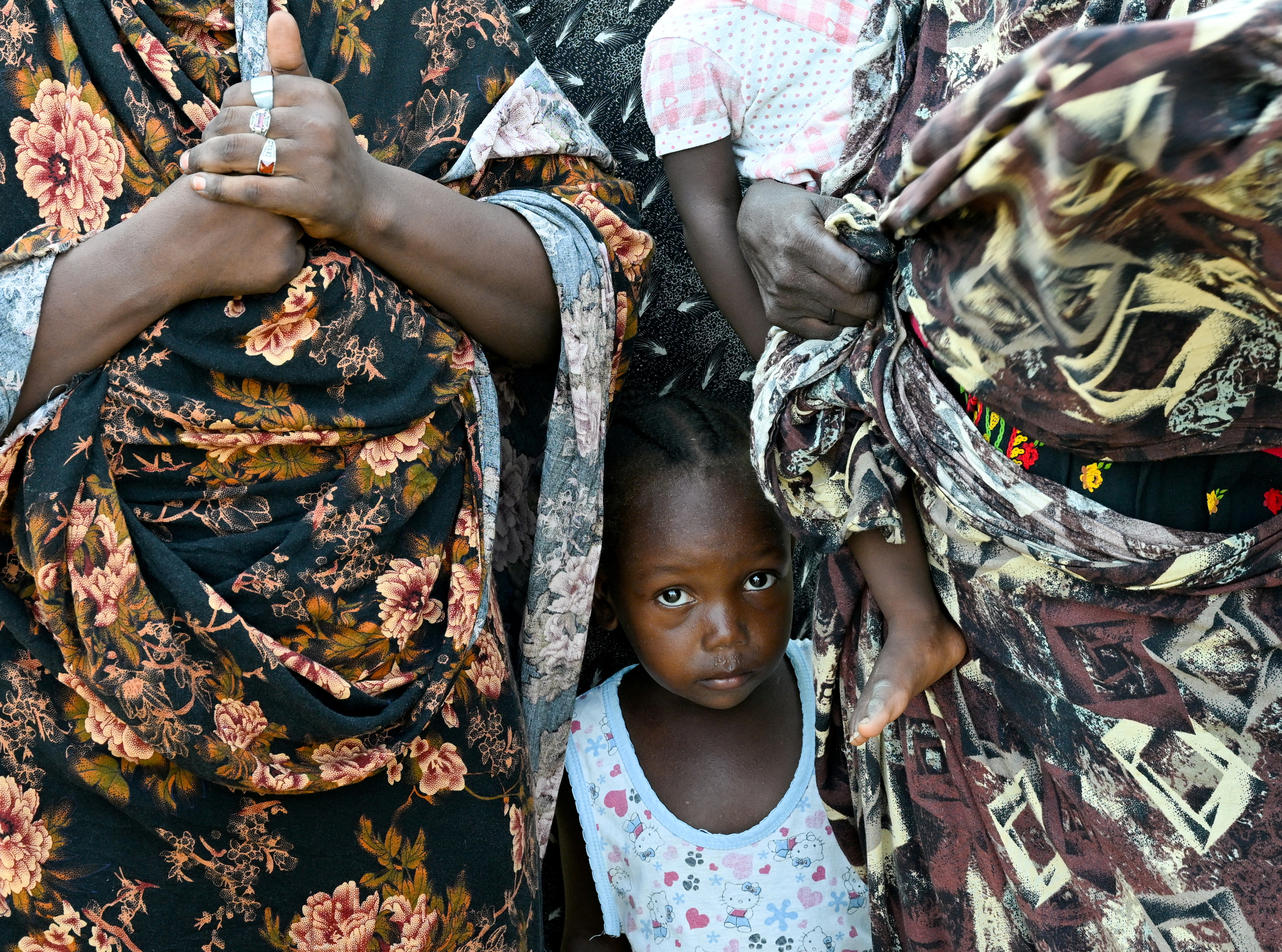 FILE PHOTO: A child stands between two women at a school turned into a shelter, in Port Sudan