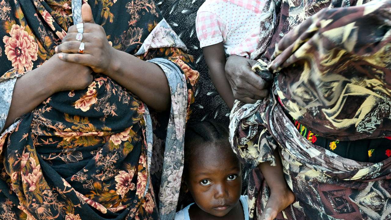 FILE PHOTO: A child stands between two women at a school turned into a shelter, in Port Sudan