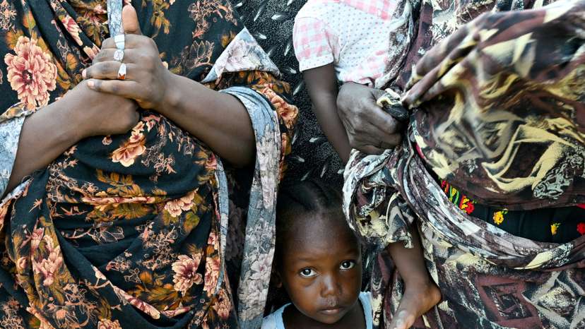FILE PHOTO: A child stands between two women at a school turned into a shelter, in Port Sudan
