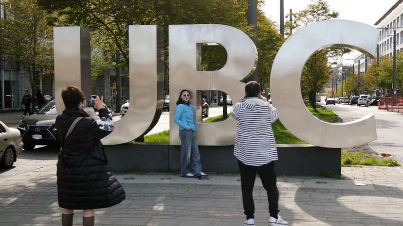 Family members take photographs at the entrance of the University of British Columbia (UBC) in Vancouver