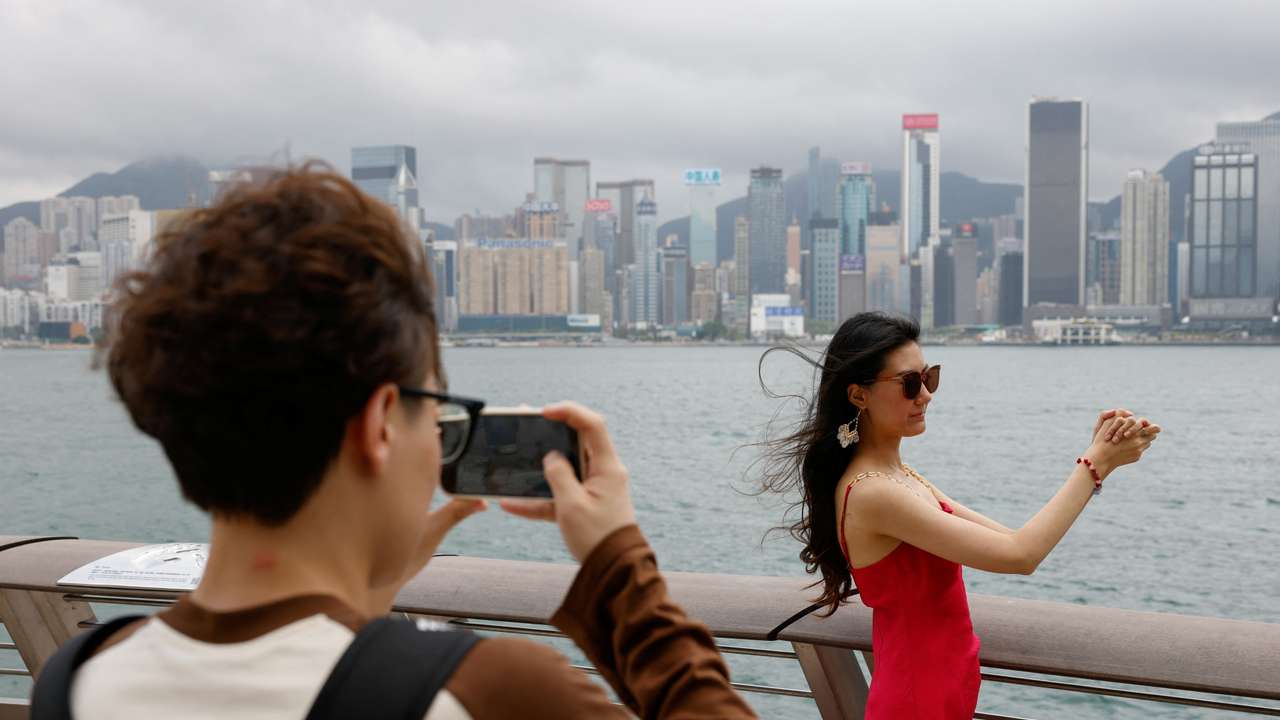 Laura Li, 28, poses for photos in front of Victoria Harbour, a day ahead of the Chinese Labour Day 'Golden Week' holidays, in Hong Kong