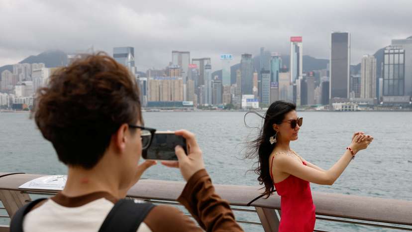 Laura Li, 28, poses for photos in front of Victoria Harbour, a day ahead of the Chinese Labour Day 'Golden Week' holidays, in Hong Kong