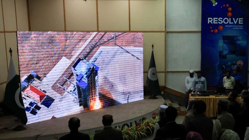 People watch a screen displaying the launch of Pakistan's Electro-Optical (EO-1) satellite, at the SUPARCO Complex, in Karachi