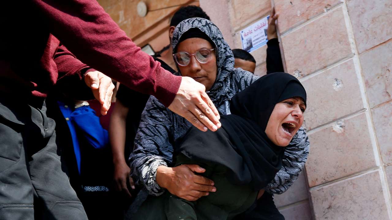 Mourners react next to the bodies of Palestinians killed in an Israeli strike