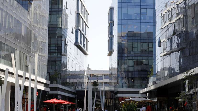 Men walk near high-rise buildings in the high-tech business area of Tel Aviv