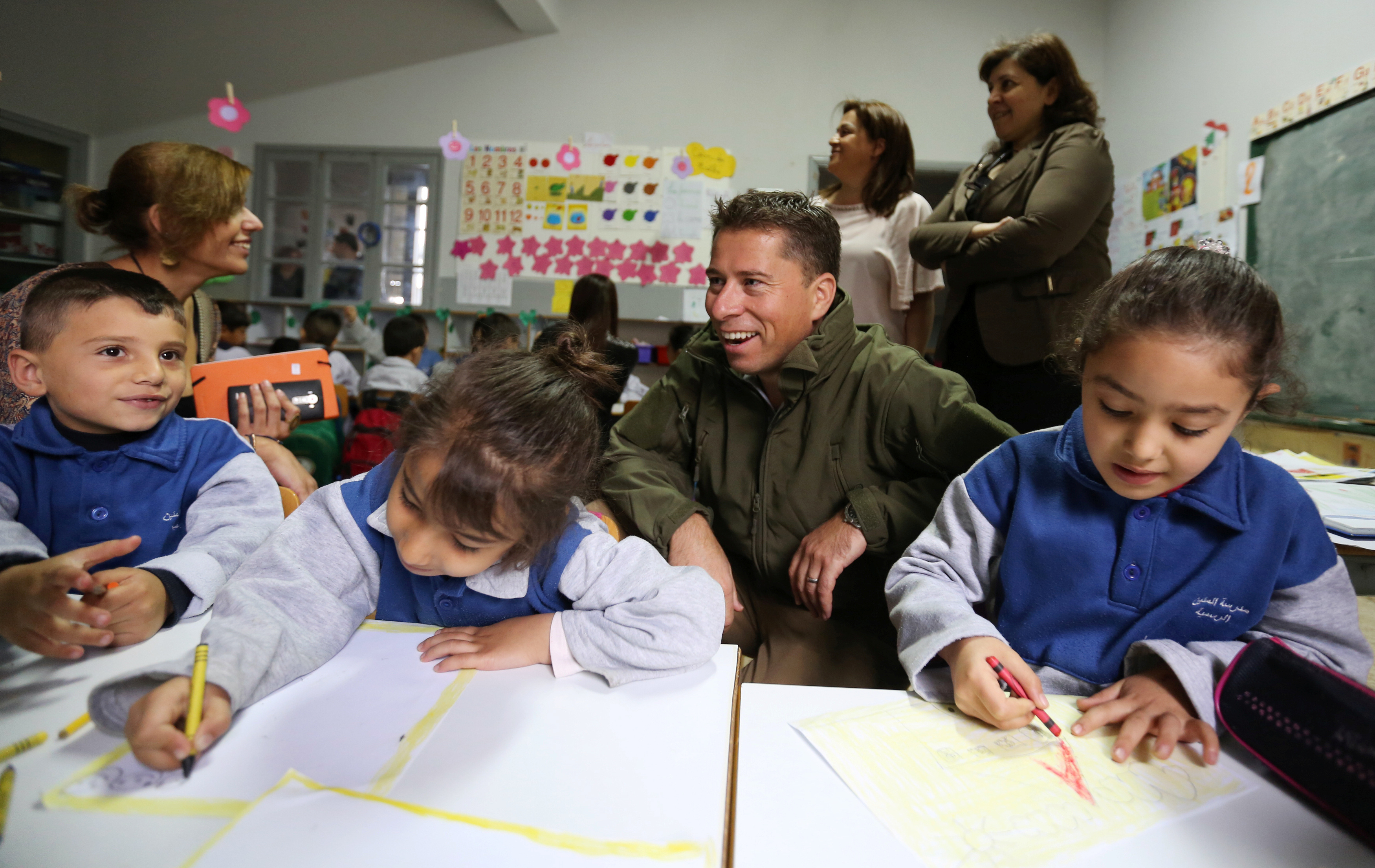 Fletcher sits near Syrian refugee children inside a classroom in Mtein Public School, at Mount Lebanon