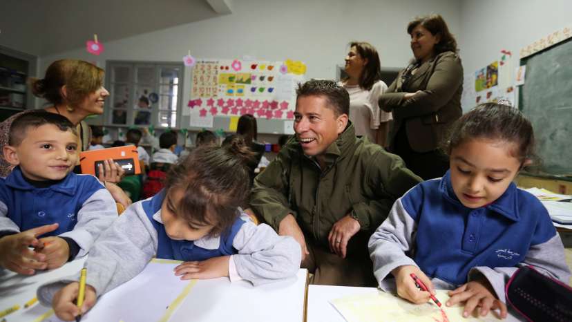 Fletcher sits near Syrian refugee children inside a classroom in Mtein Public School, at Mount Lebanon
