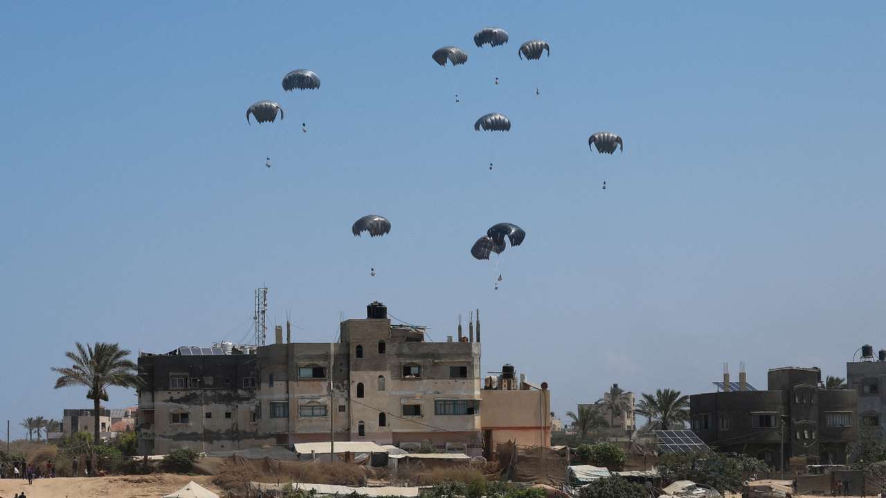 Aid packages dropped from an airplane descend over Gaza, in Zawayda