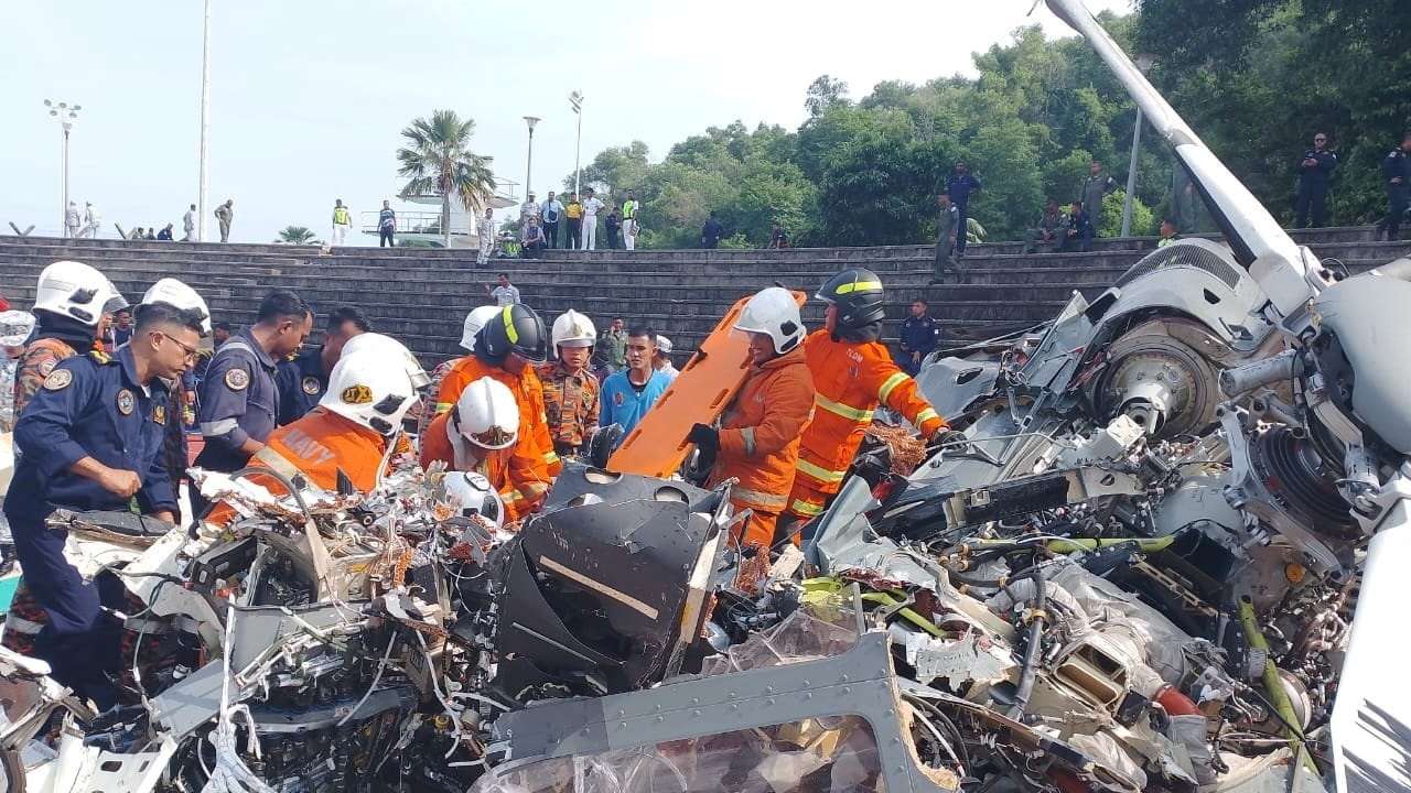 Emergency crew work at the site of a helicopter crash in Lumut, Perak