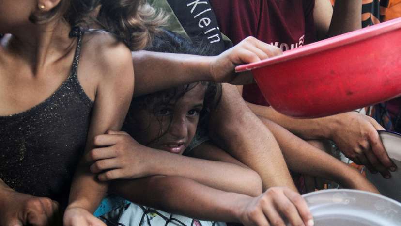 FILE PHOTO: Palestinians wait to receive food cooked by a charity kitchen in the northern Gaza Strip