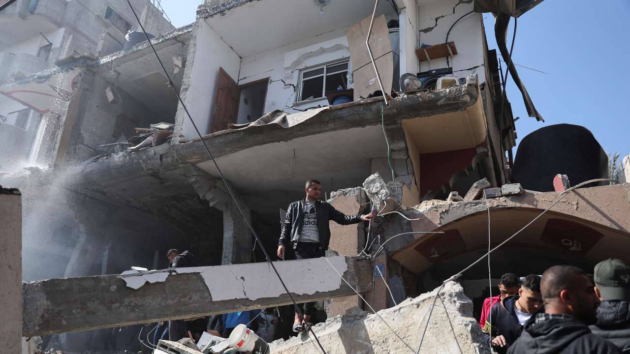 Palestinians inspect the site of an Israeli strike on a house, in Rafah