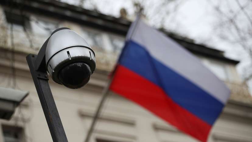 A security camera is seen, and a flag flies outside the consular section of Russia's embassy in London