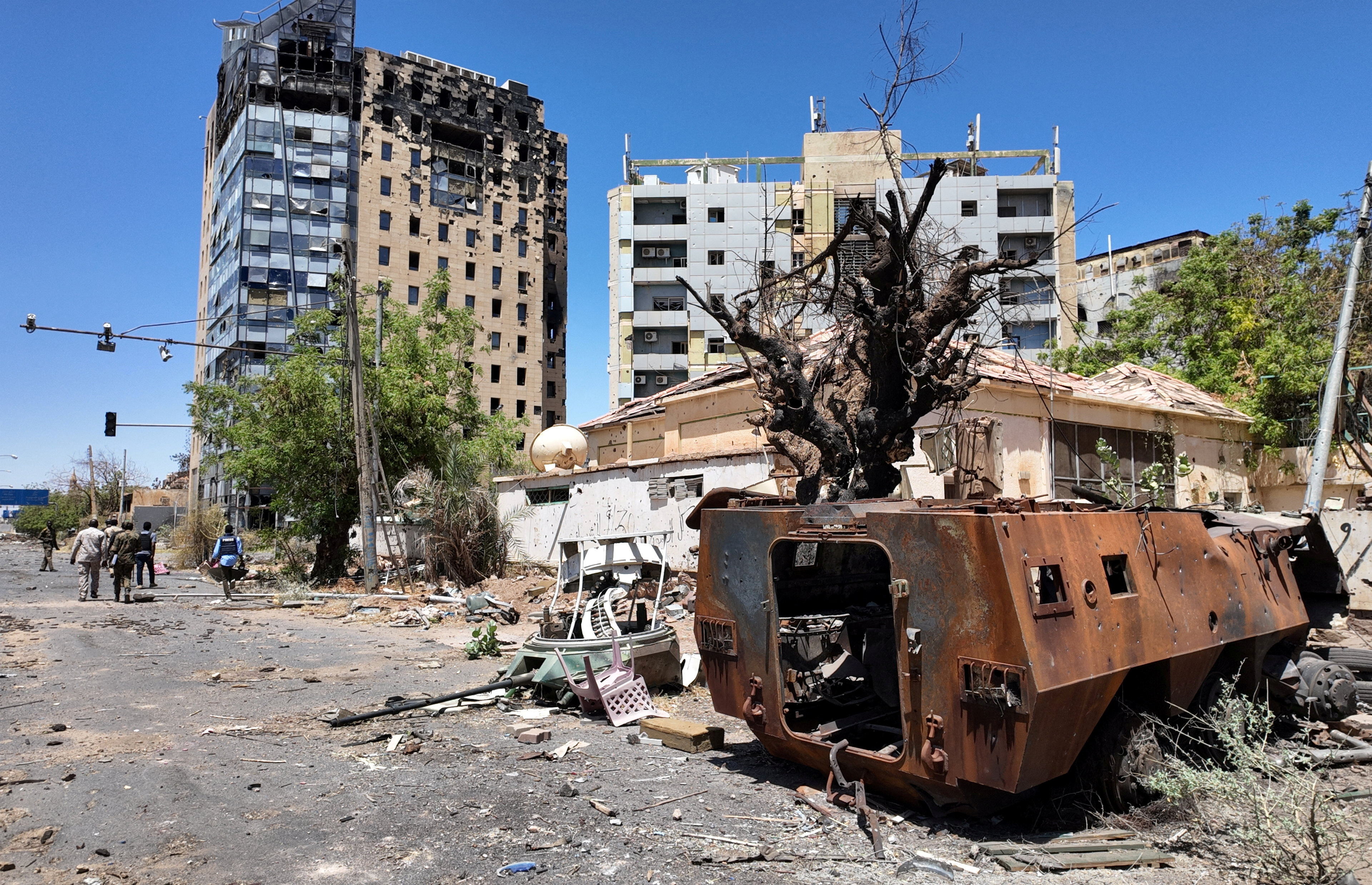 FILE PHOTO: Members of army walks next to destroyed military vehicle and bombed buildings in the state of Khartoum