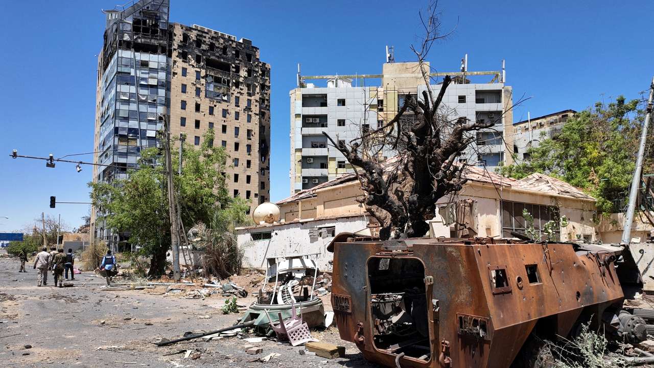 FILE PHOTO: Members of army walks next to destroyed military vehicle and bombed buildings in the state of Khartoum