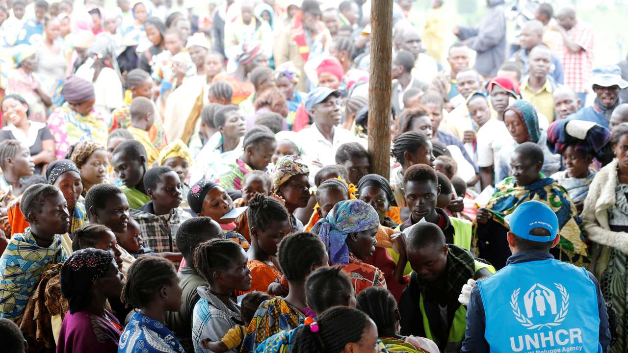 A UN worker monitors Congolese refugees who fled from the Democratic Republic of Congo by boat across Lake Albert, upon arrival at United Nations High Commission for Refugees (UNHCR) in settlement camp in Kyangwali