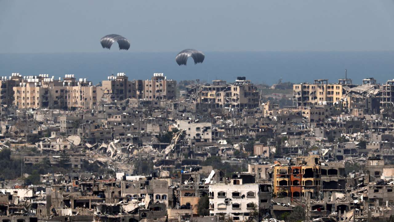 Humanitarian aid falls through the sky towards the Gaza Strip, as seen from Israel's border with Gaza