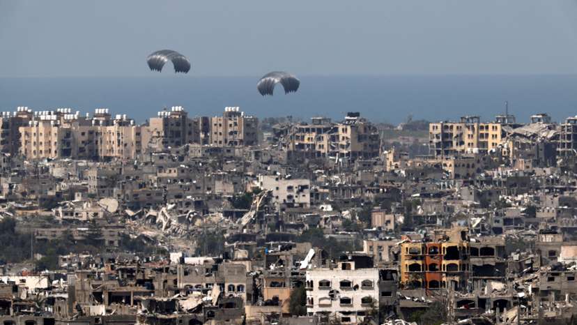 Humanitarian aid falls through the sky towards the Gaza Strip, as seen from Israel's border with Gaza