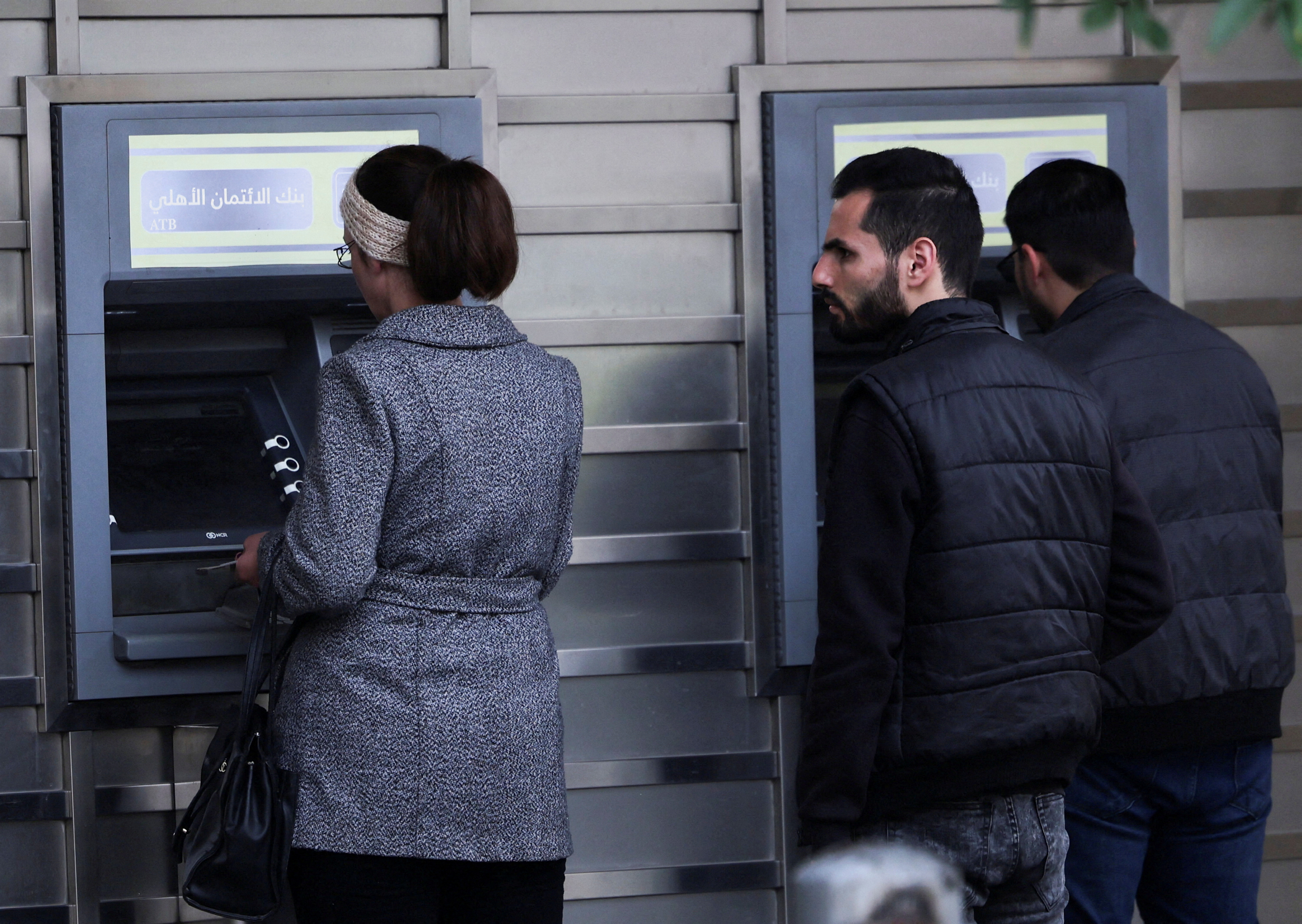 FILE PHOTO: People wait in front of ATM machine, after rebels seized the capital and ousted Syria's Bashar al-Assad, in Damascus