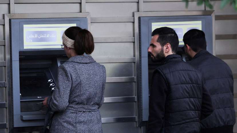 FILE PHOTO: People wait in front of ATM machine, after rebels seized the capital and ousted Syria's Bashar al-Assad, in Damascus