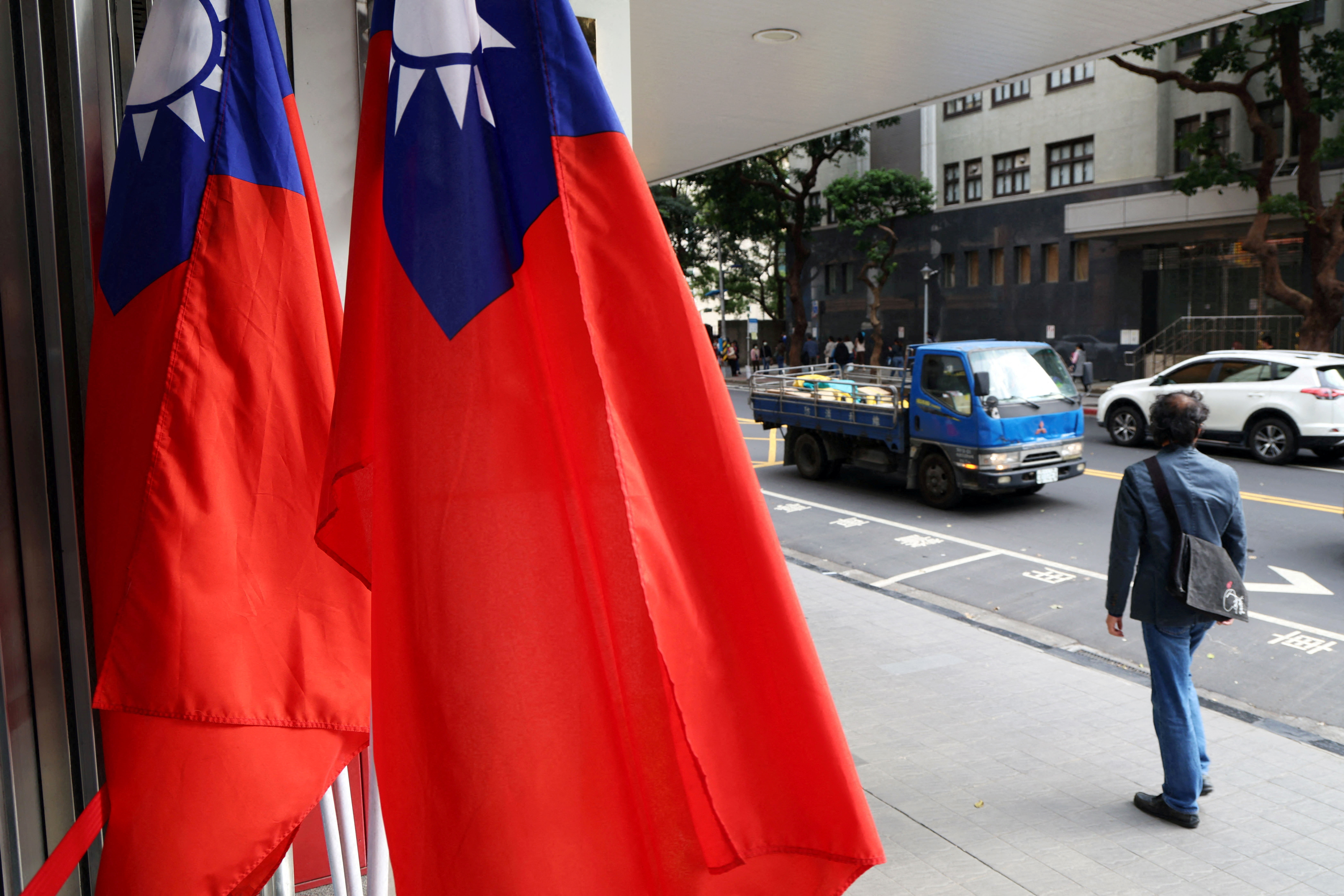 FILE PHOTO: A man walks past Taiwanese flags on a street in Taipei