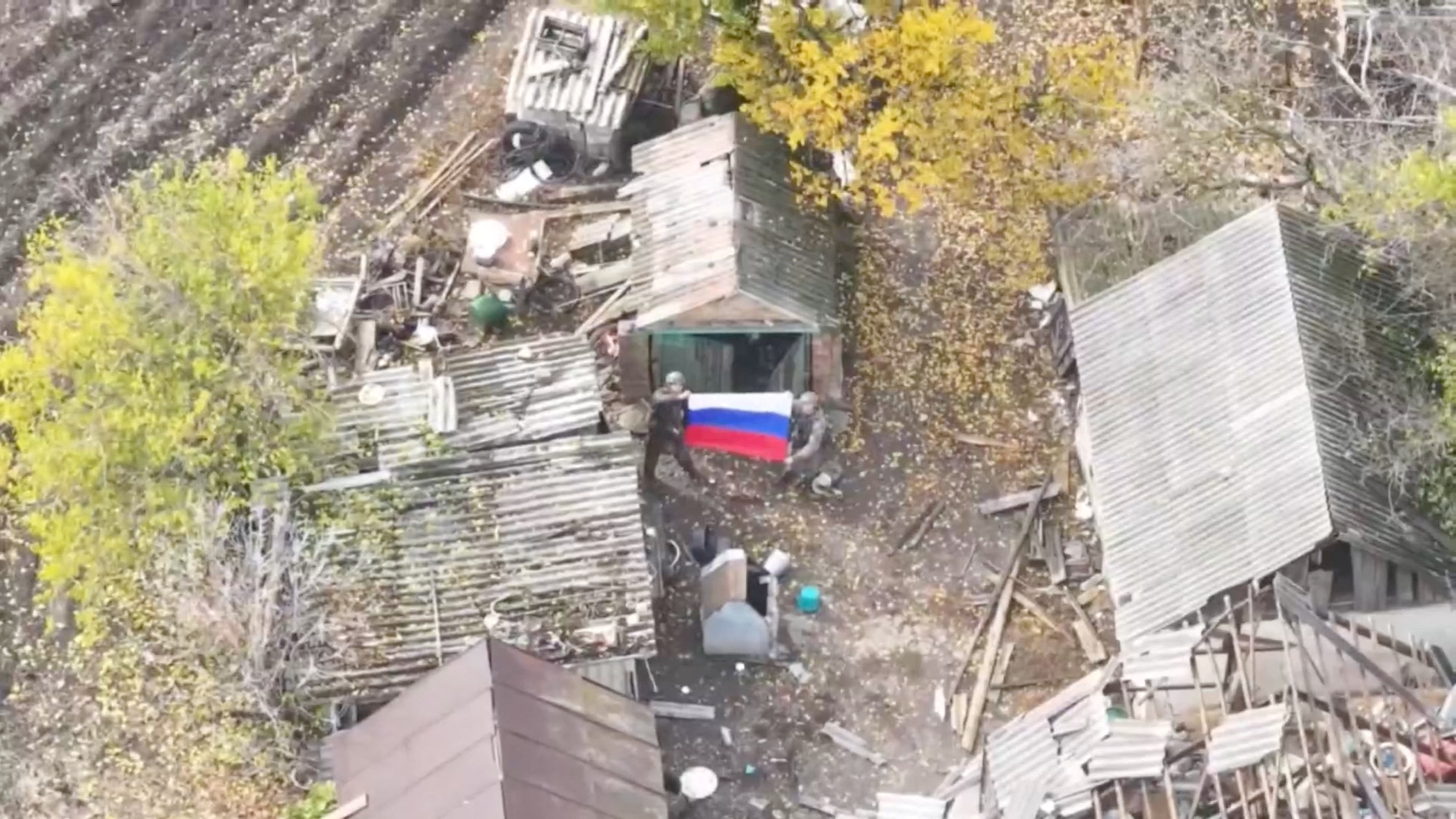 Russian soldiers hold a national flag after taken control of the village of Vyshneve