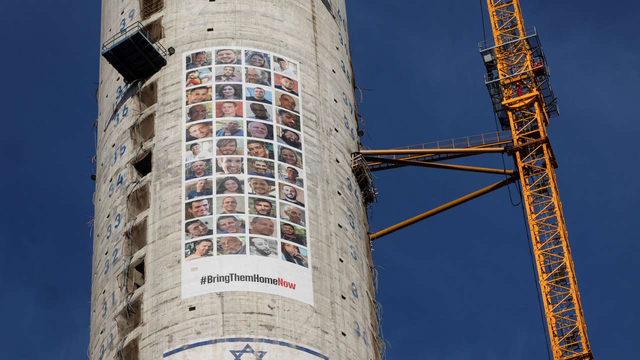 Pictures of hostages kidnapped during the deadly October 7 attack by the Palestinian Islamist group Hamas from Gaza, are seen next to an Israeli flag on a building under construction, in Tel Aviv
