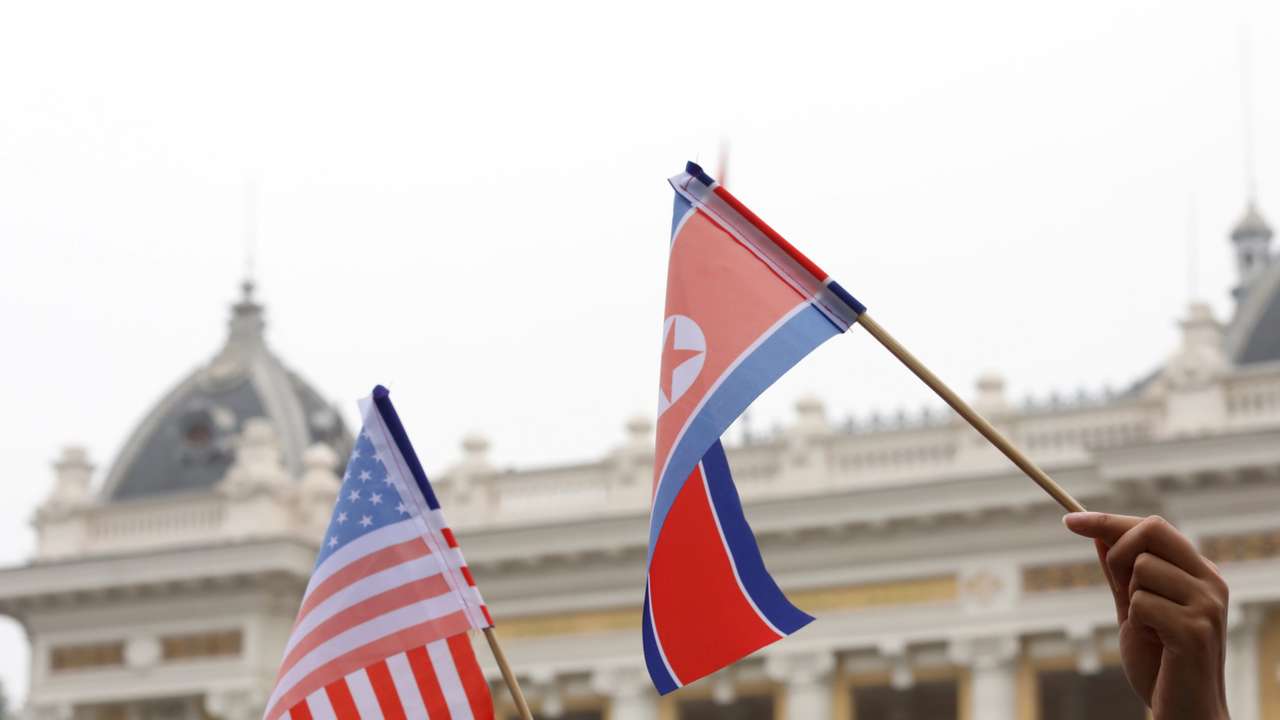 Residents hold US and North Korean flags while they wait for motorcade of North Korea's leader Kim Jong Un en route to the Metropole Hotel for the second US- North Korea summit in Hanoi