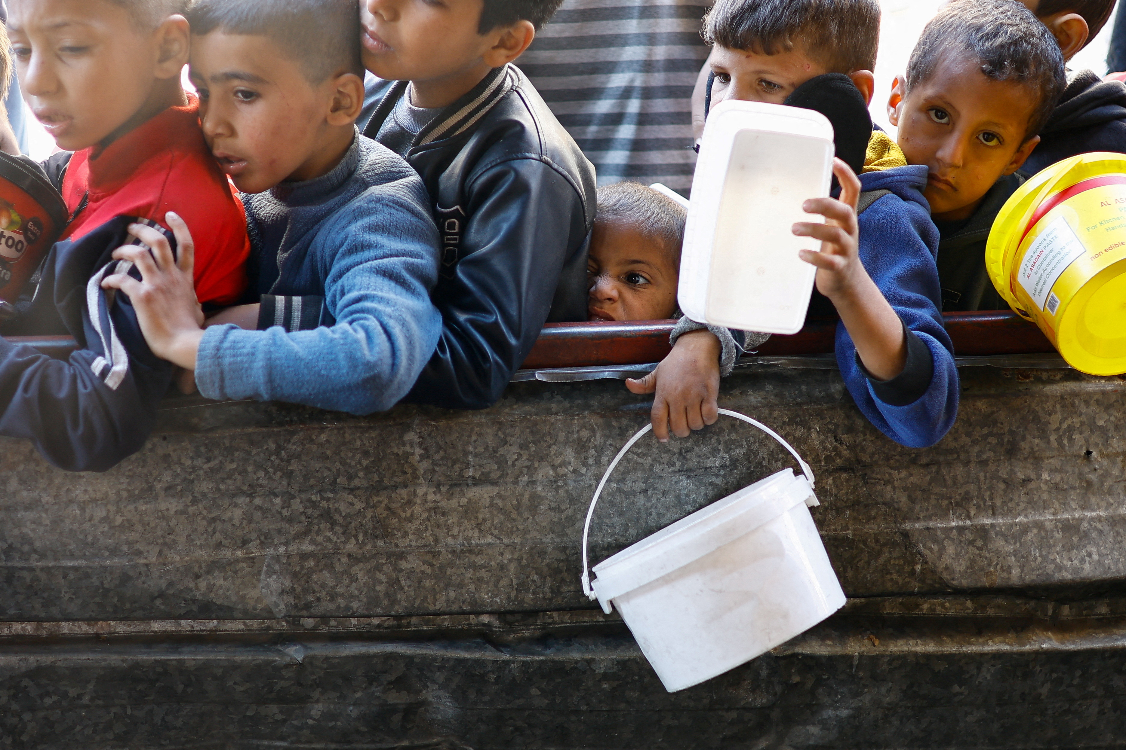 Palestinians wait to receive food amid shortages of food supplies, in Rafah in the southern Gaza Strip